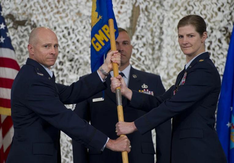 four people holding an american flag and a baton