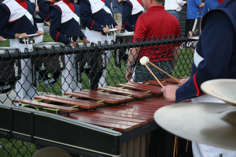 musical instruments are arranged near a fence and behind it, on people wearing blue jackets