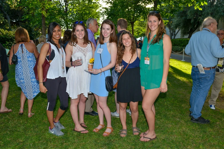 many girls standing together in the grass at an outdoor event