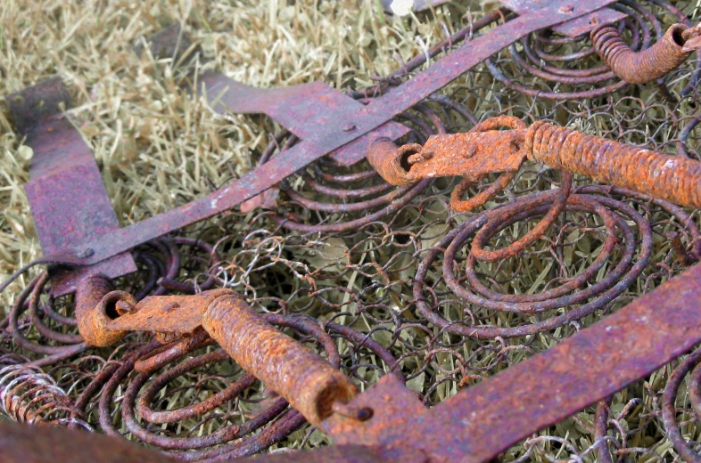 old rusty industrial parts in the grass and a few wires