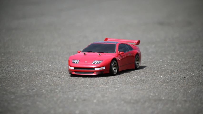 a toy red car sitting on the street