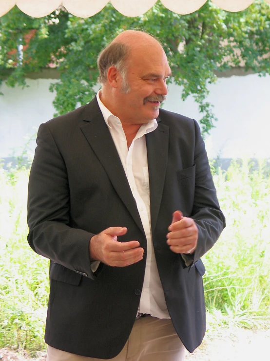 an older man wearing a suit is standing in the grass