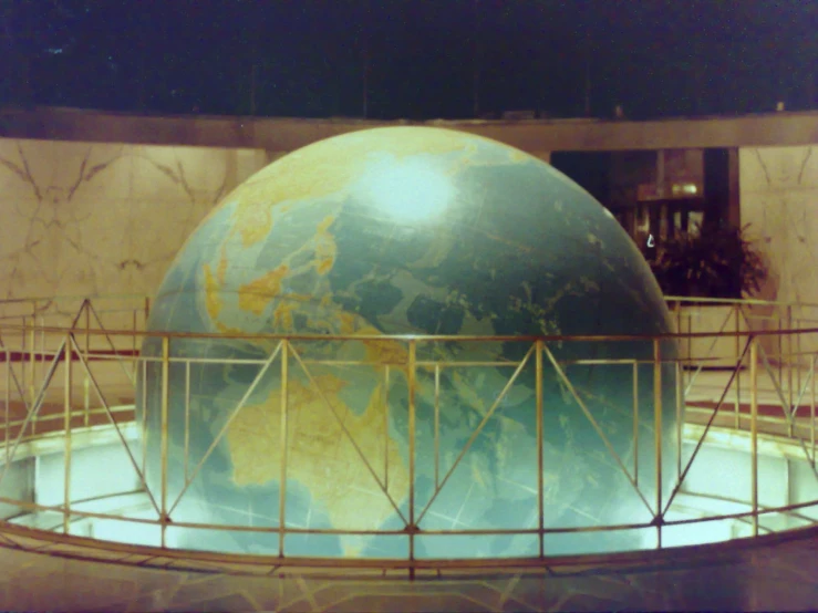 a large globe is displayed with fencing in front of it
