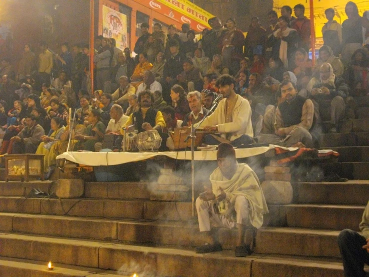 smoke pouring out of a bowl as a conductor plays music in front of a crowd