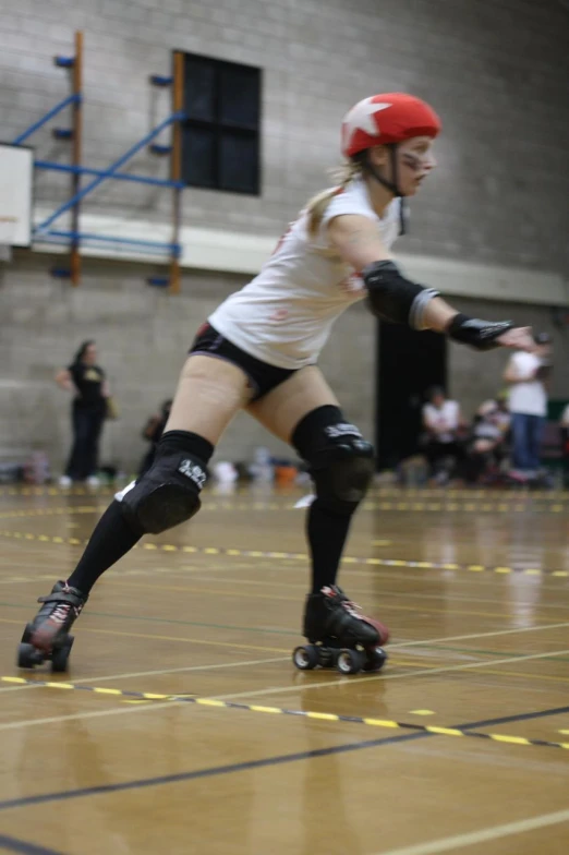 a woman in roller skates moving down a hard wood floor