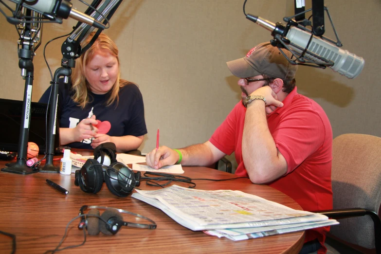 the two people are sitting at the table looking at the news