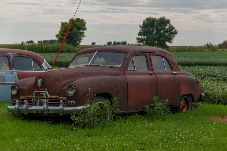 an old run down car is sitting in the grass