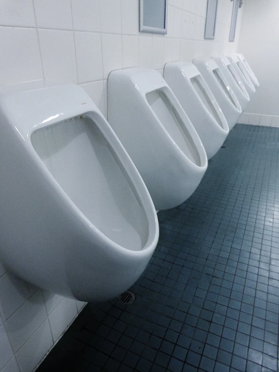 a white bathroom filled with urinals next to a wall