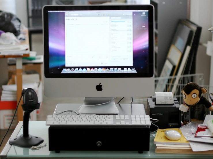 an apple desktop computer with a monkey toy sitting next to it