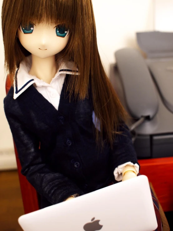 a doll is holding an apple laptop in front of a camera