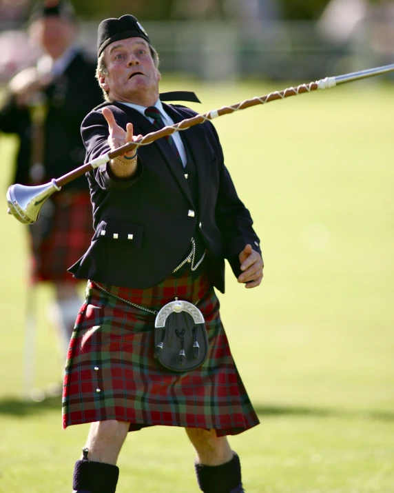 man in kilt and jacket holding a steel mallet