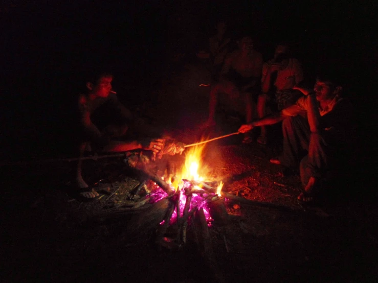 people roasting marsh on fire in dark area
