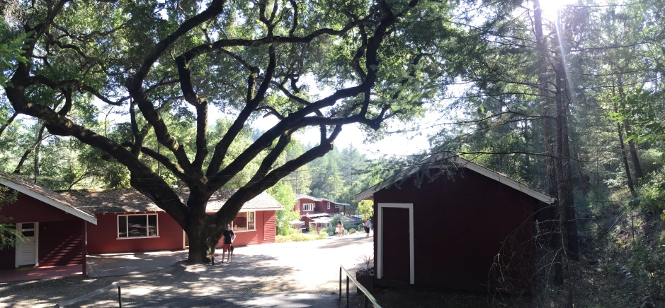 an old fashioned red shed sits in front of some buildings