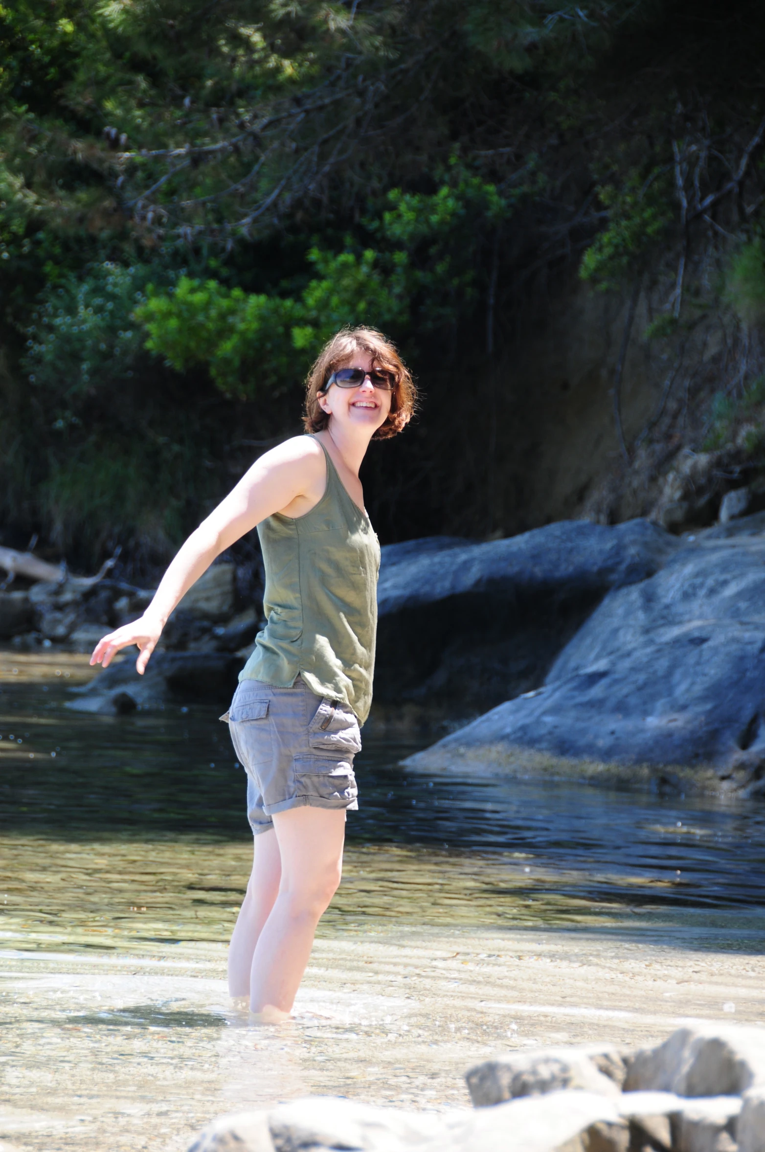 a woman is standing in the water on a beach