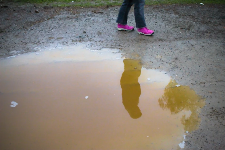 a girl in pink clogging boots, leaning on a dle of water