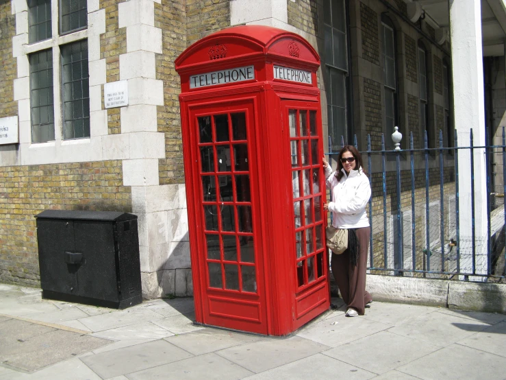 a lady standing in front of a phone booth