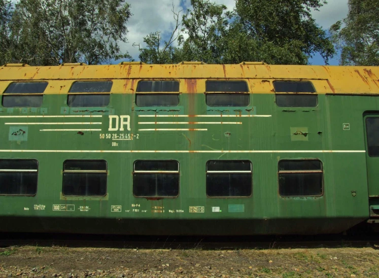 a green train parked near some trees