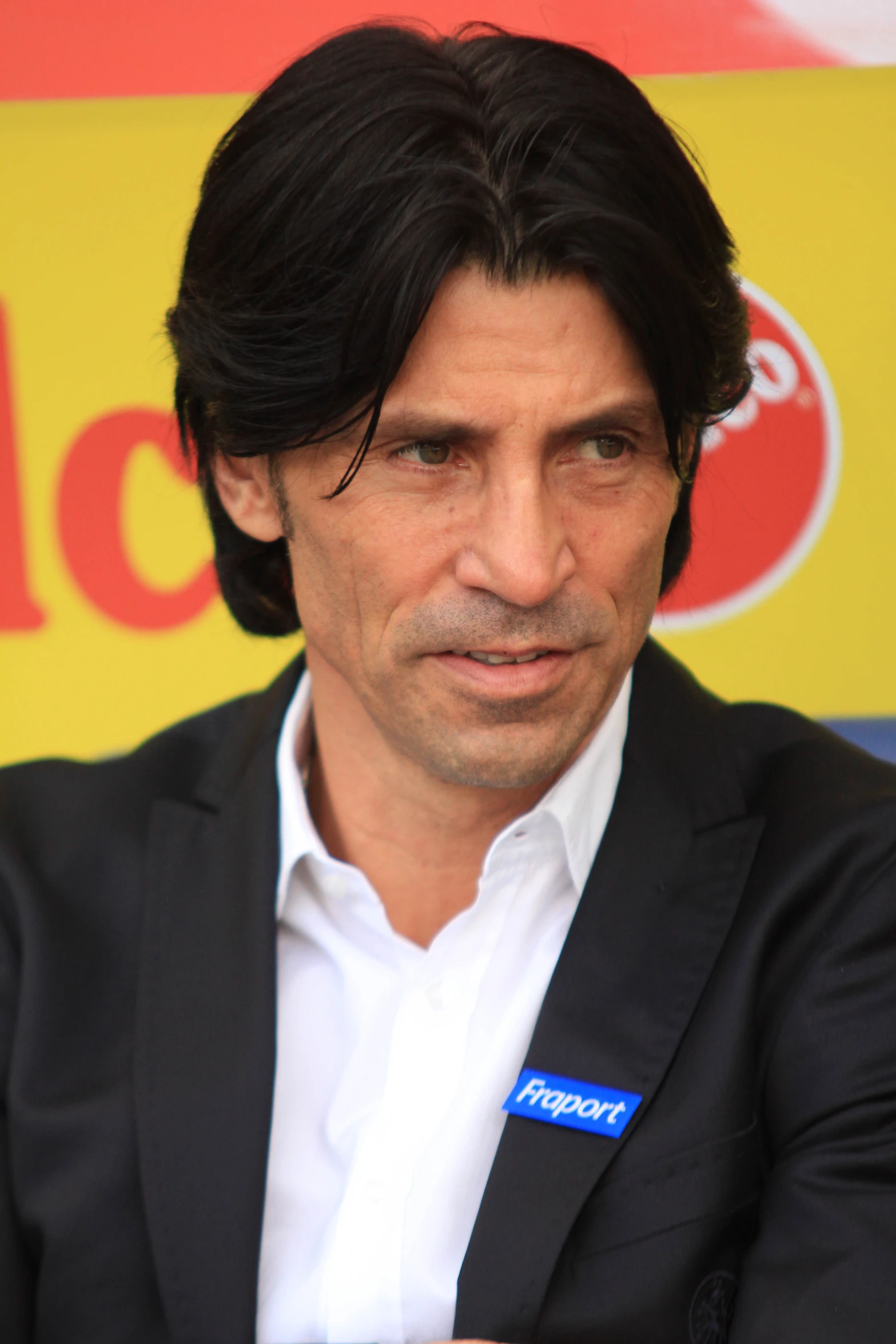 a man in a black suit with a white shirt and a pepsi logo on his jacket