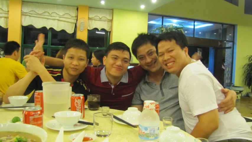 three men posing for the camera at a table