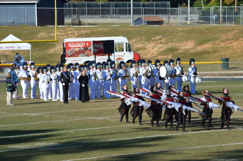 a military band marches along on a grassy field