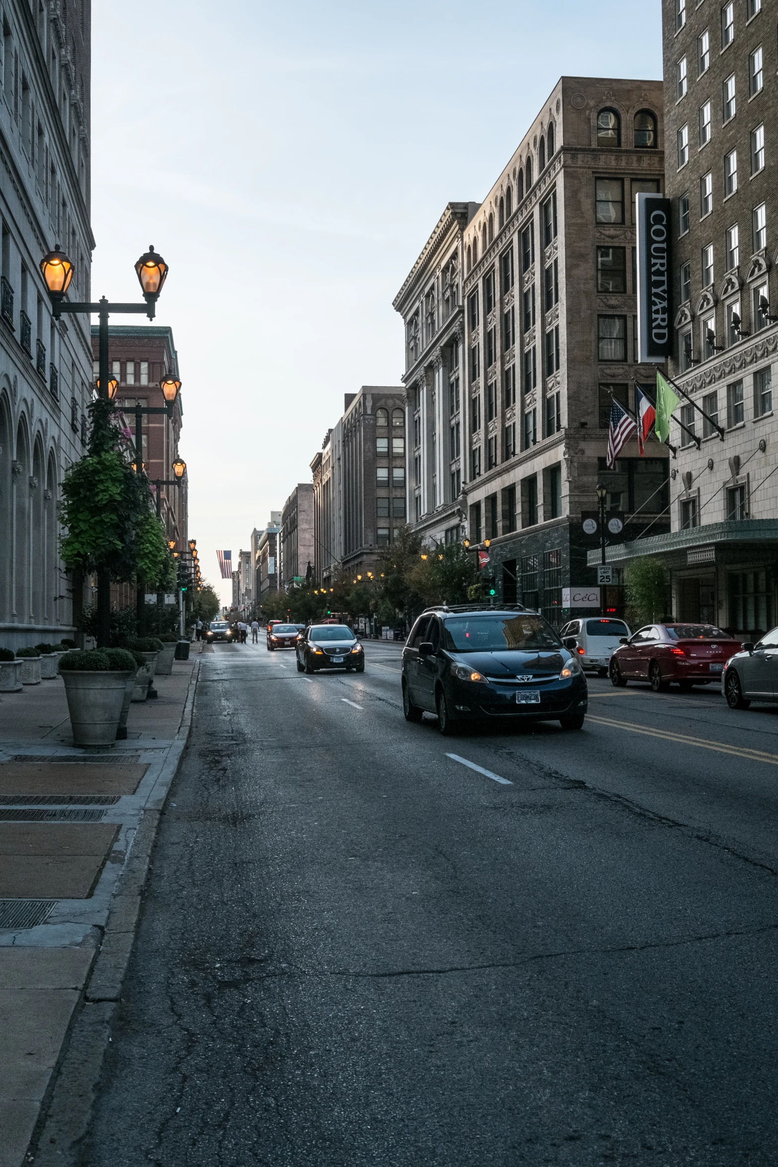 several cars drive down a city street near tall buildings