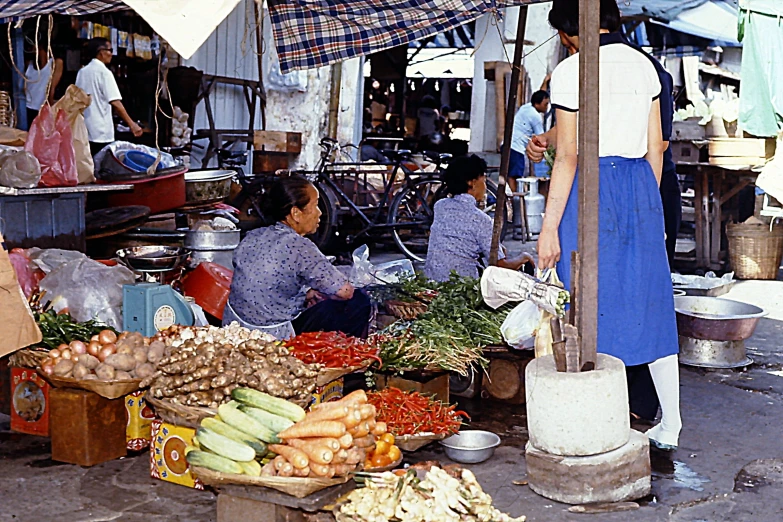 people gathered around fruit and vegetable stand under umbrellas