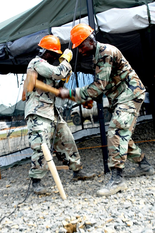 two people in uniform holding sticks near an umbrella