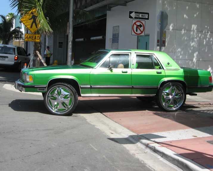 a green car is parked in front of a street corner