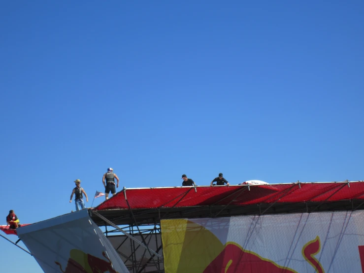 four people doing tricks on a kite on a sunny day