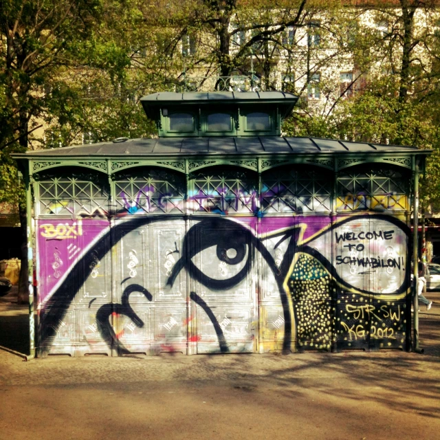 a gazebo covered in colorful graffiti is seen on the street