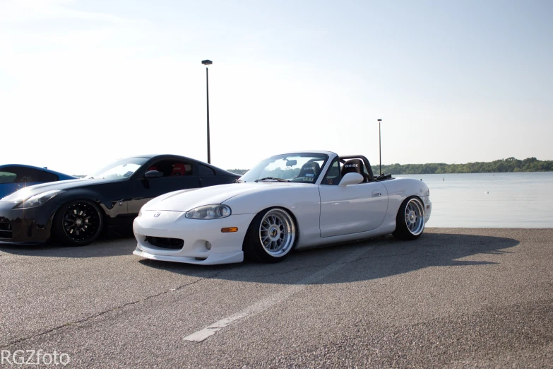 two white sports cars in parking lot next to water