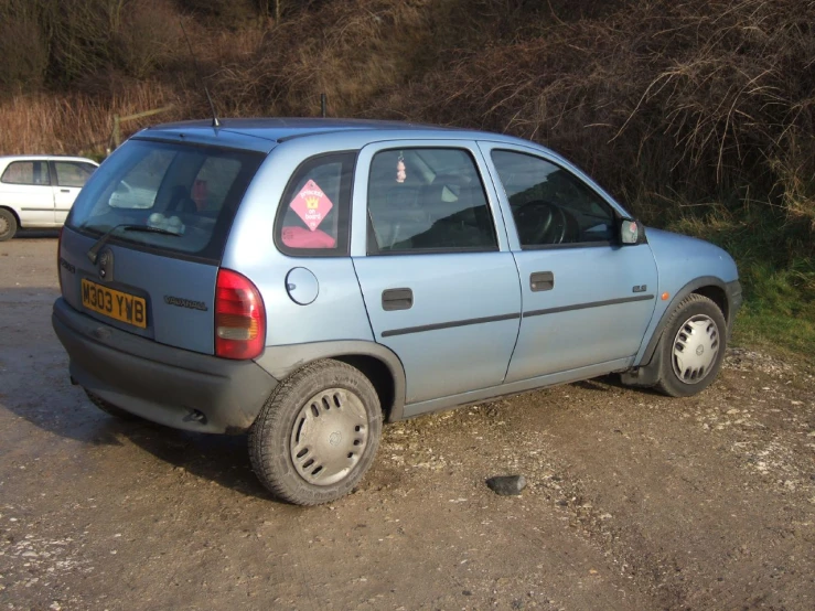 the silver car is parked on a dirty parking lot