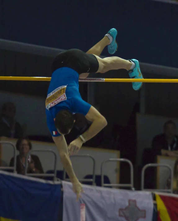 a male pole vault competitor is high in the air