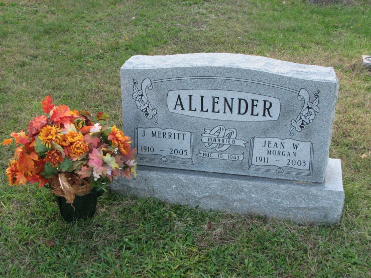 a tombstone marker and a vase with flowers are shown in a cemetery