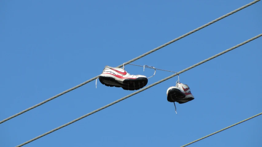 two pairs of white shoes hanging on a wire