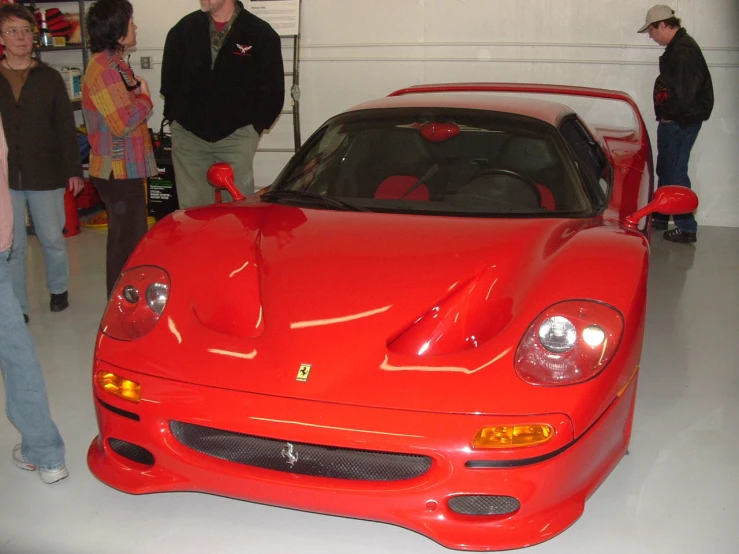 a man looks at a ferrari sports car in a garage
