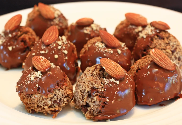 several dark chocolate covered desserts, covered in nuts