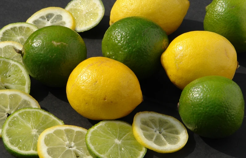 several lemons, limes and lemon slices on the ground