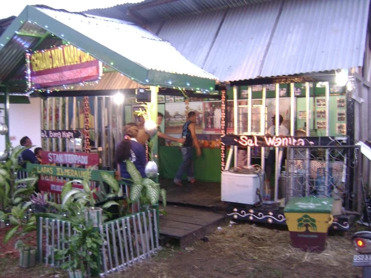 the front of a small green shop with people standing outside