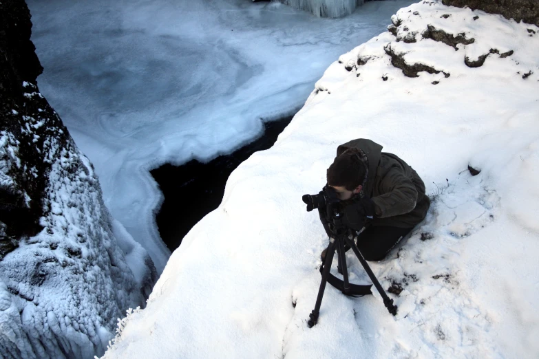 a man looking at snow on the side of a rock