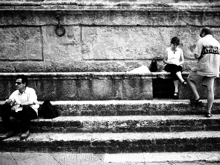 two people sitting on a step talking and reading