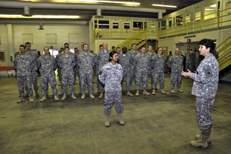 a woman speaks to a group of people in military uniform