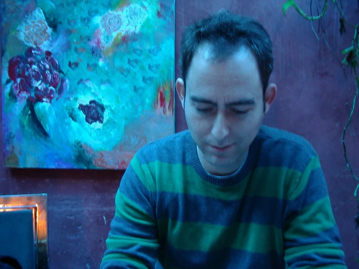a man in a colorful sweater writing on his lap top