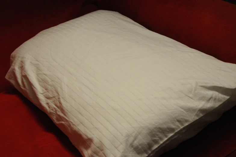 a white square pillow sits on the edge of a red couch