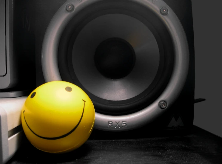 a yellow ball near some speakers and a black keyboard