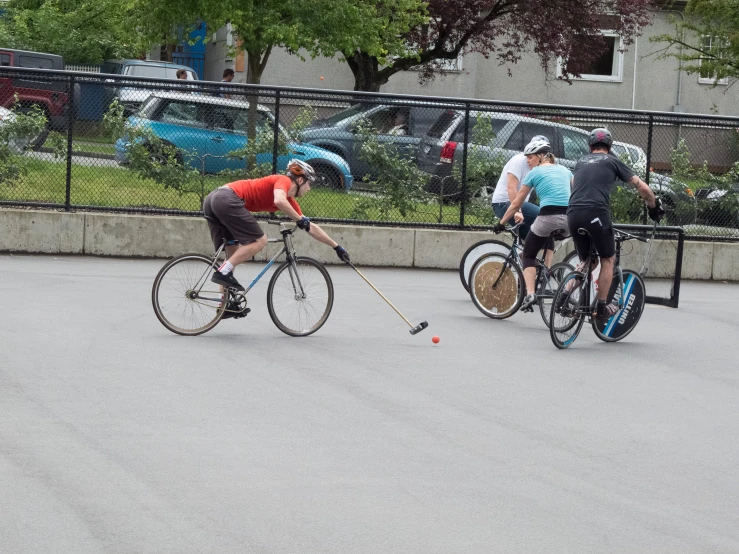 two people ride bikes down the street with a racket strapped to one