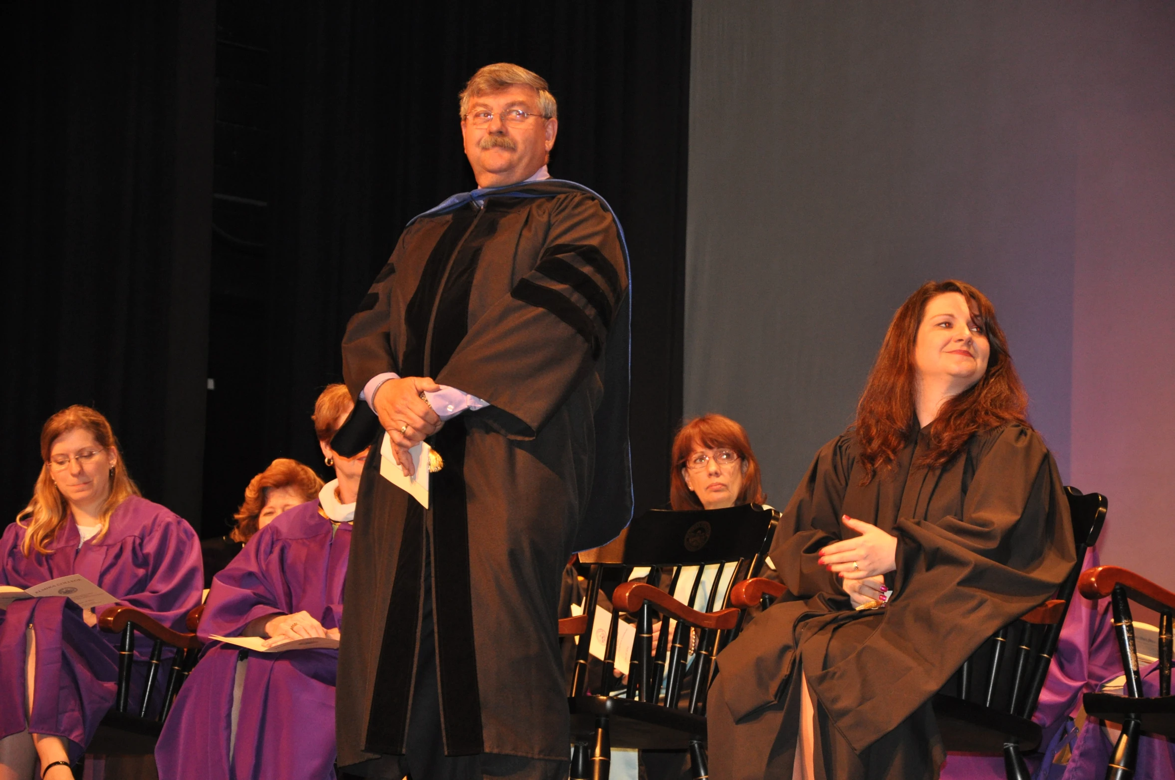 a graduating student standing in a ceremony with others