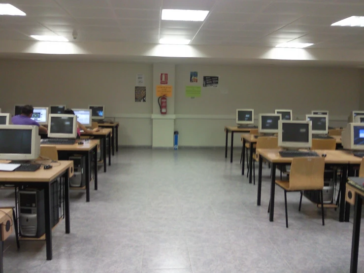 rows of desks are empty with computers on top
