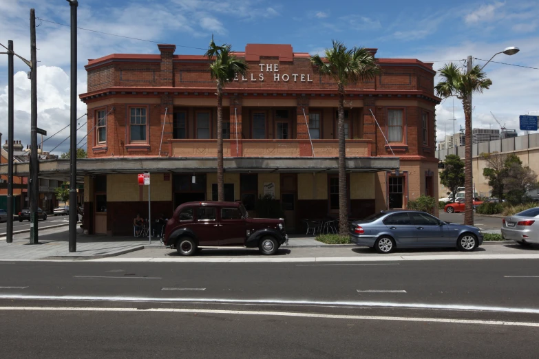 a large brown building on the corner with cars in front of it