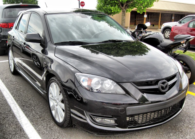 a parked black car next to some other cars